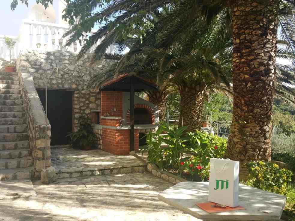 Der Hof der Apartment-Villa zum Verkauf auf Pag ist mediterran angelegt und bepflanzt.